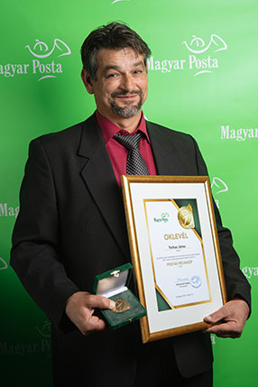 A képen Farkas János látható a postás példakép díjjal és oklevéllel a kezében.