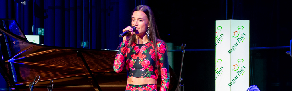 A képen Gubik Petra énekel egy Magyar Posta rendezvényen