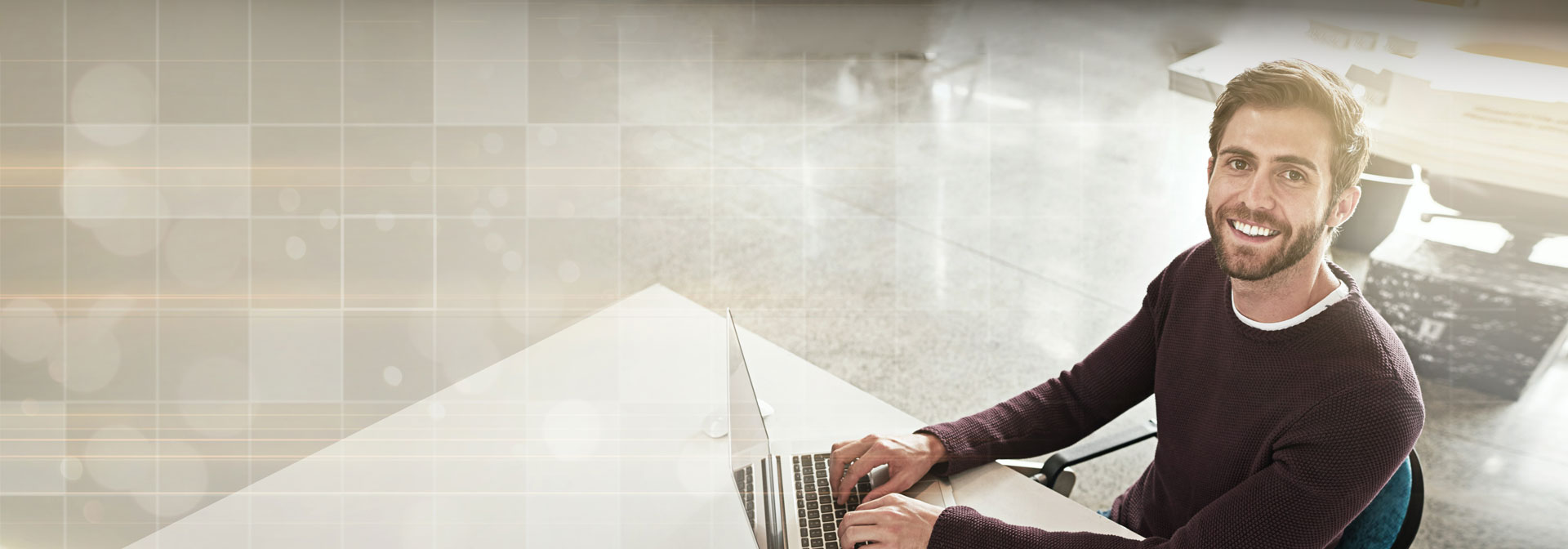 A képen egy mosolygó laptopon dolgozó féfi látható